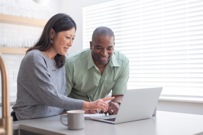 A couple use a laptop computer in their kitchen
