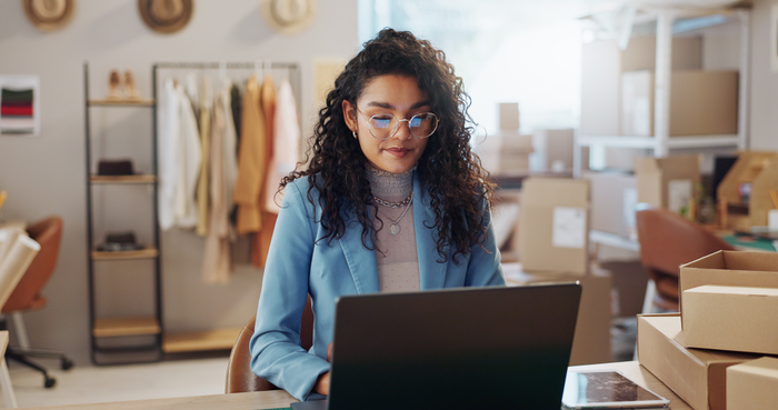 Woman, fashion and designer with laptop in logistics, research or small business management at boutique. Female person or entrepreneur with computer for inventory or storage check at retail store
