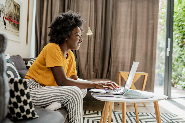 Woman sitting on the couch and typing at a laptop